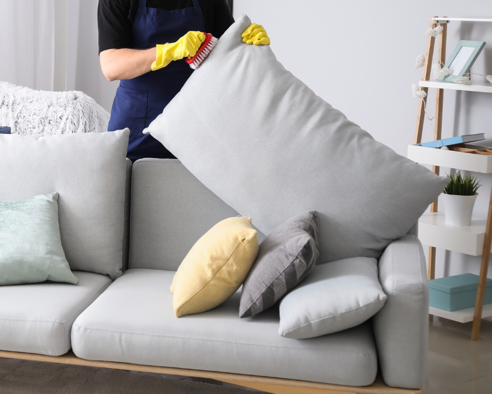 Nettoyage minutieux sous les coussins d’un canapé dans une maison de vacances