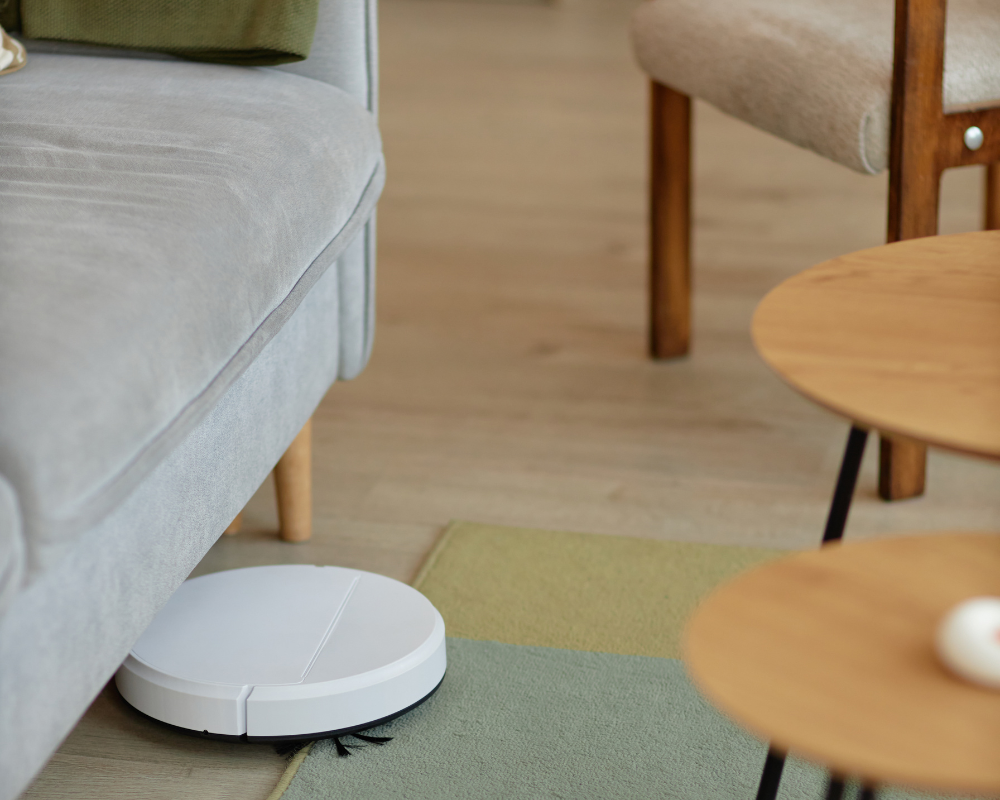 Robot aspirateur nettoyant sous le canapé avant une réception à la maison