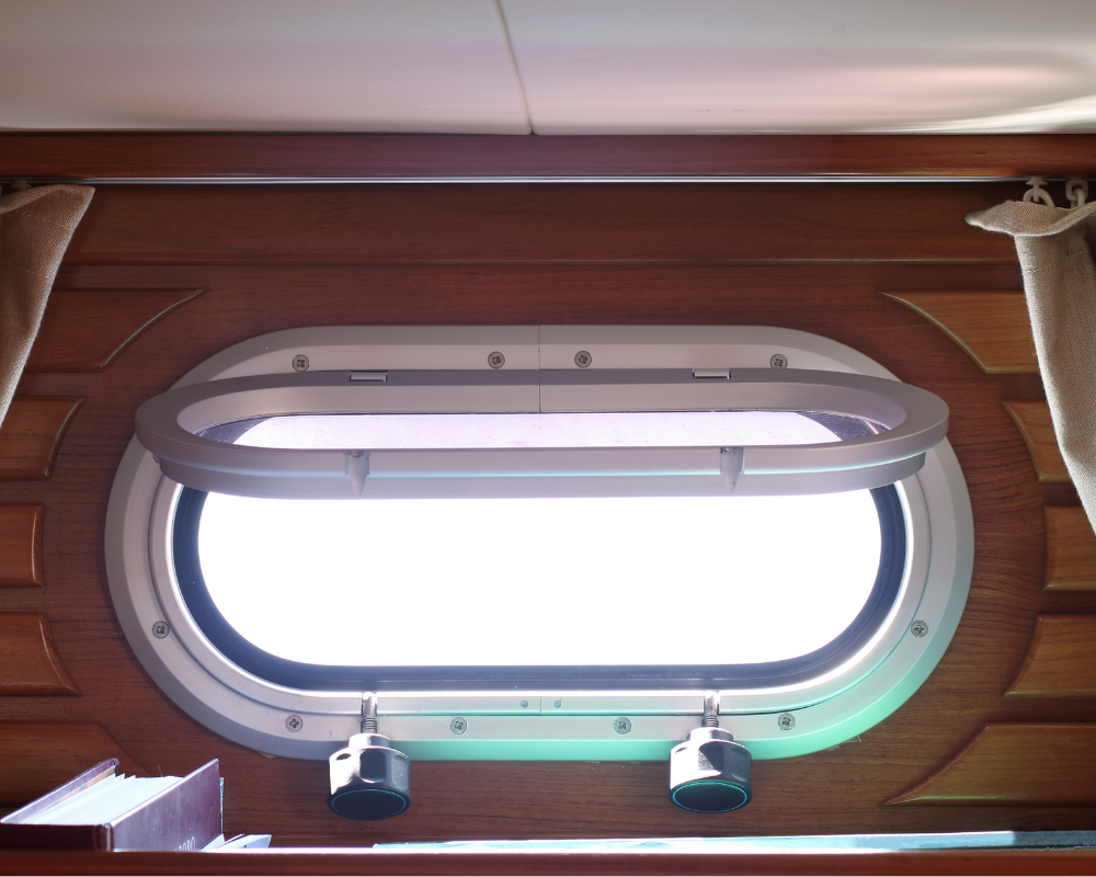 Hublot de cabine ouvert laissant entrer la lumière naturelle – aération d’un bateau après l’hiver selon les astuces de Max
