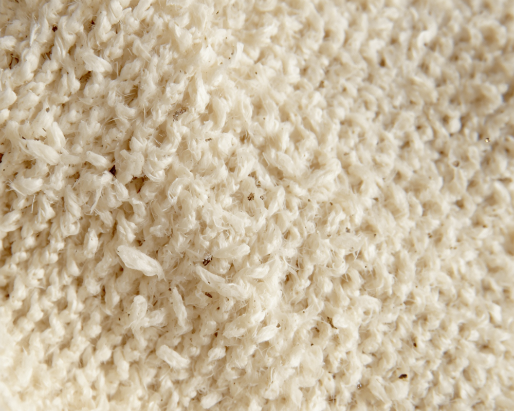 Zoom sur tissu bouclette crème de canapé haut de gamme, fibres épaisses et texture moelleuse captant la lumière naturelle, Les astuces de Max Maison Max Clean, nettoyage canapé à Marseille, Aix-en-Provence et région PACA