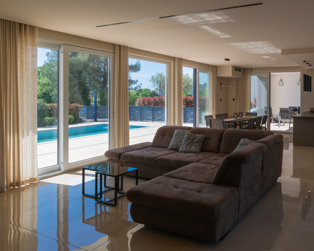 Salon ouvert sur terrasse et piscine dans une villa haut de gamme en Provence, exposition directe entre intérieur et extérieur impactant canapés et textiles, expertise Maison Max Clean – Les astuces de Max, région PACA Aix-Marseille