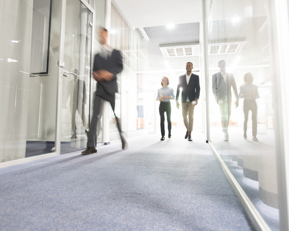 Employés marchant dans un couloir d'entreprise lumineux sur une moquette à fort trafic en région PACA