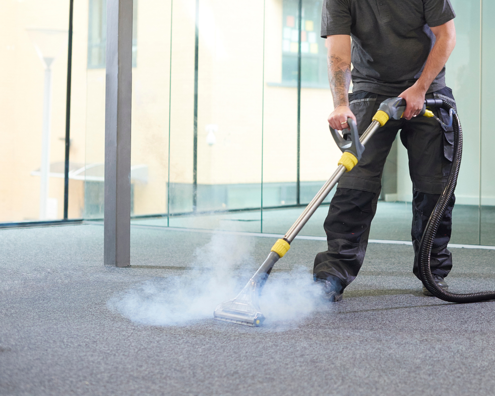 Technicien professionnel effectuant le nettoyage en profondeur d'une moquette de bureau par injection-extraction.